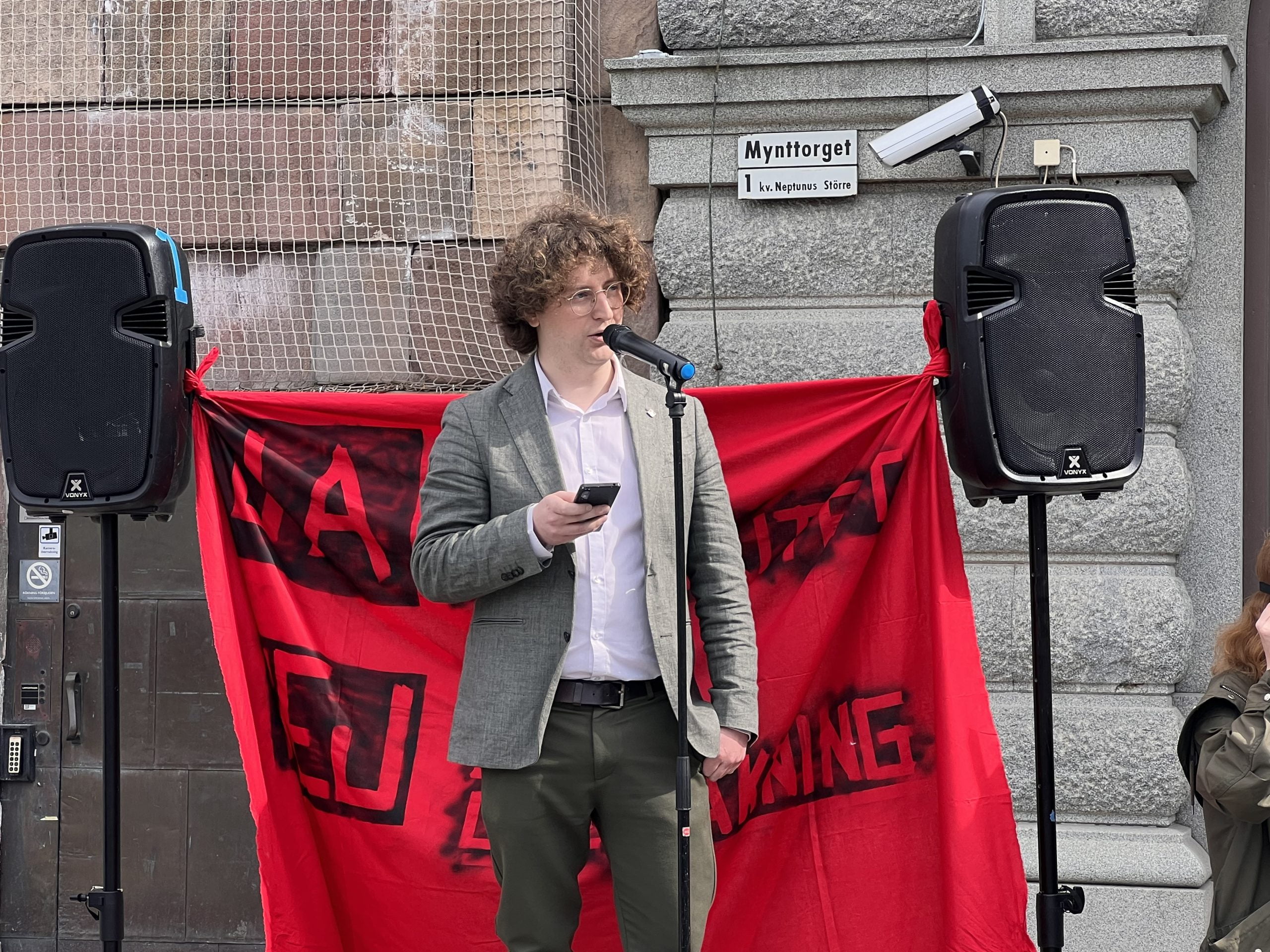 Mikael Blomstrand, styrelseledamot hos Centerstudenter, talar vid demonstration. En banderoll med texten "ja till integritet, nej till övervakning” syns i bakgrunden.
