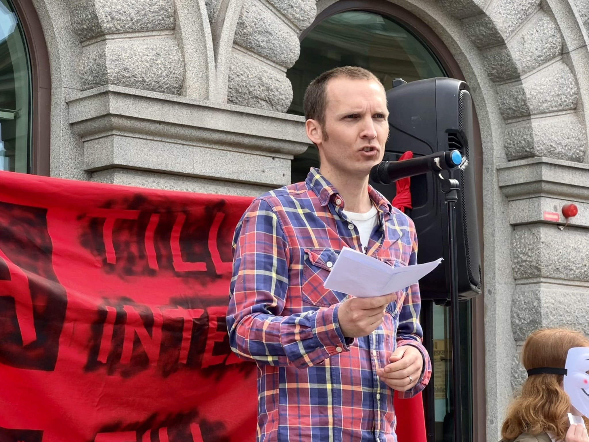 Samuel Skånberg (Kamratdataföreningen Konstellationen) står på scen. En banderoll med texten "ja till integritet, nej till övervakning” syns i bakgrunden.